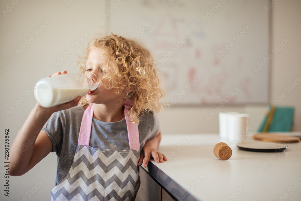 Adorable little boy and his mom in white aprons cooking together in the  kitchen Stock Photo