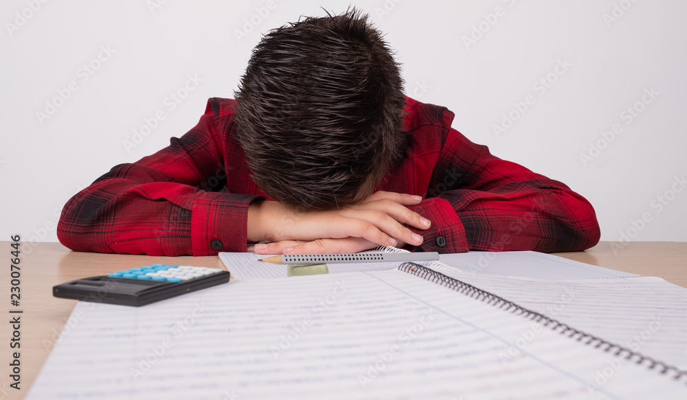 sad boy with hands on his head at the table at school sad boy with hands on his head at the table at school