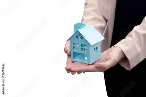 Close up of female hands holding a small metal blue house model with copy space on the left, insolated on white background, with clipping path. Property auction and home buying and caring concept.
