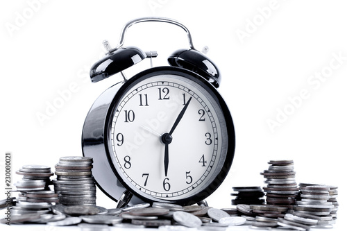 Black alarm clock and stack of coins for time of business and finance concept.