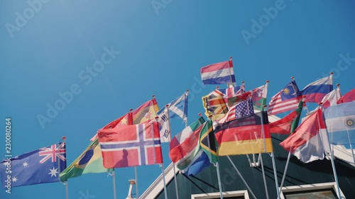 Flags of different states of the world are fluttering in the wind at the roof of an old wooden house