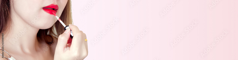 banner design for makeup fashion portrait of woman with color bright red lips, girl in her hand holds a lip gloss on pink pastel background, advertising sell and sale in website concept, copy space