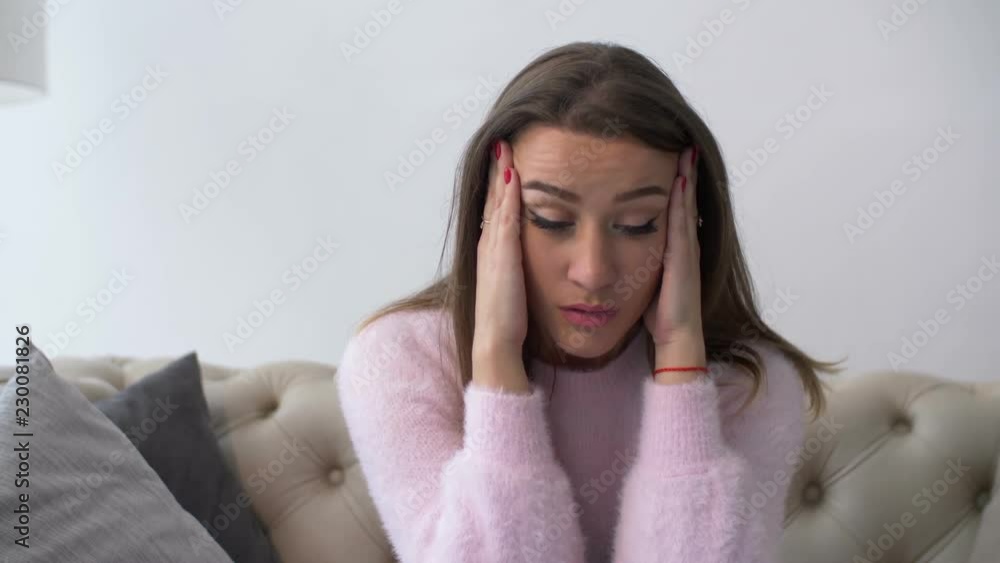 Portrait of desperate millennial woman sitting on sofa in deep depression, holding her head in hands, expressing hopelessness and disappointment indoors. Beautiful female in midlife crisis at home. Portrait of desperate millennial woman sitting on sofa in deep depression, holding her head in hands, expressing hopelessness and disappointment indoors. Beautiful female in midlife crisis at home.