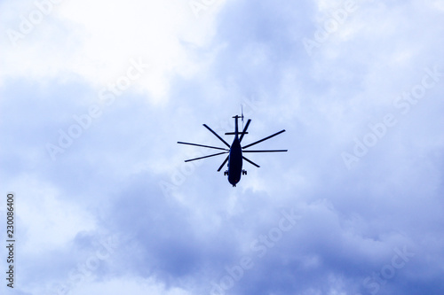a large military helicopter hovers in the sky. A camouflaged helicopter flies at high speed.