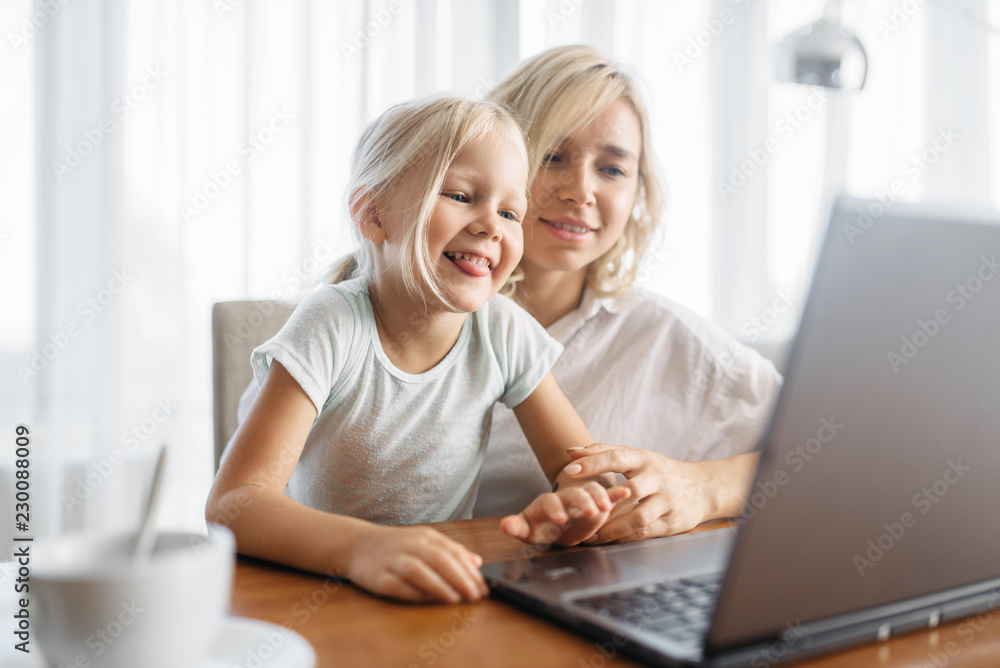 Smiling mother and child uses laptop at home Smiling mother and child uses laptop at home