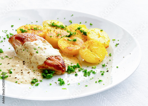 chicken filet under sour cream mustard sauce garnished with potato and sprinkled with parsley