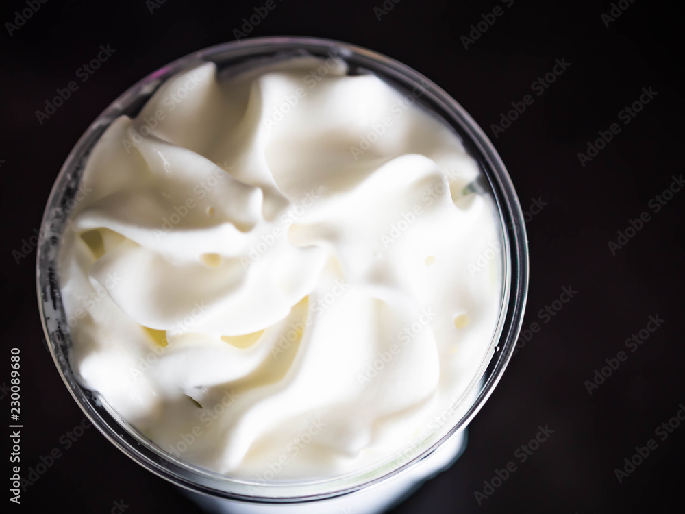 Top view and closeup of sweetened whipped cream in plastic grass with black background. Top view and closeup of sweetened whipped cream in plastic grass with black background.