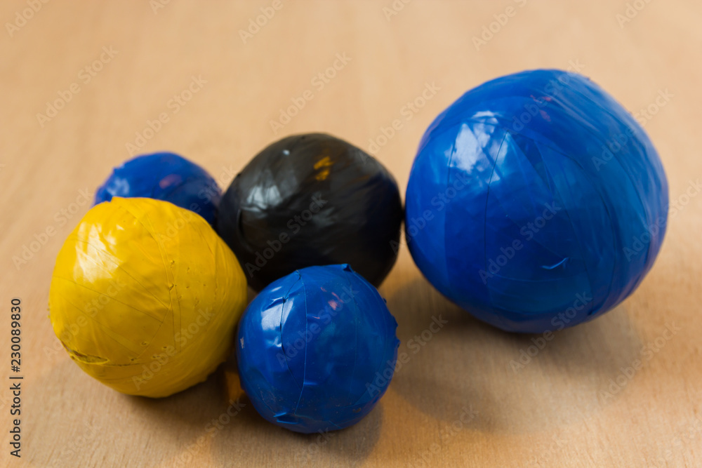 colourful duct tape balls of blue, black and yellow in various sizes made by a child on school