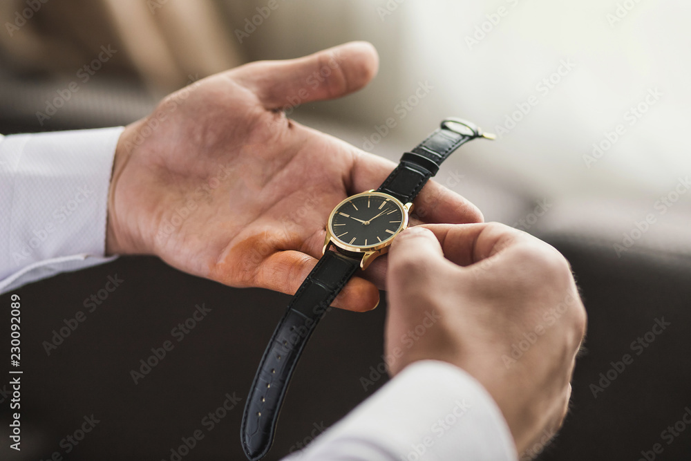 Fototapeta premium businessman checking time on his wrist watch, man putting clock on hand,groom getting ready in the morning before wedding ceremony