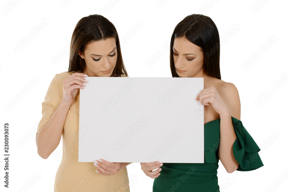 Two young women holding blank board, looking down on board Two young women holding blank board, looking down on board