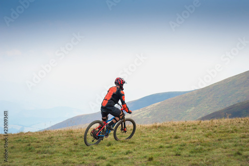 Professional cyclists riding the downhill mountain bike on the mountain trail. Two cyclists are preparing to ride mountain bike on single trail in Carpathians, Borzhava, Ukraine. 21 August, 2018.