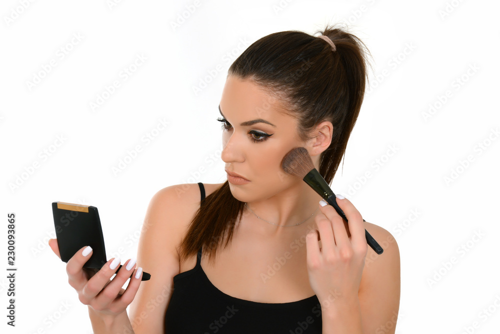Beautiful woman applying make-up, holding make up brush and small mirror Beautiful woman applying make-up, holding make up brush and small mirror