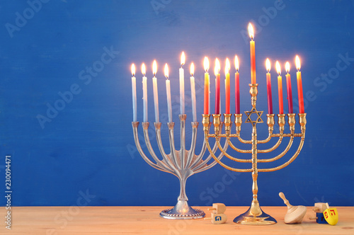 Image of jewish holiday Hanukkah background with traditional spinnig top, menorah (traditional candelabra) and burning candles.