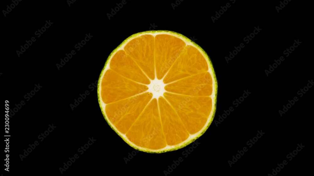 Cross section of a green tangerine. Rotating on the turntable. Isolated on the black background. Close-up. Macro.