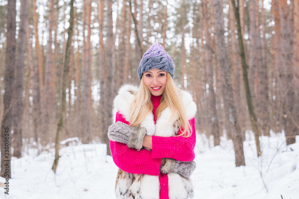 Fototapeta premium Nature, fashion and people concept - Young attractive blond woman posing in the winter park.