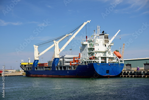 Wide view of a cargo freighter at dock unloading 36 meter wind energy turbine blades at the Port of Corpus Christi, Texas