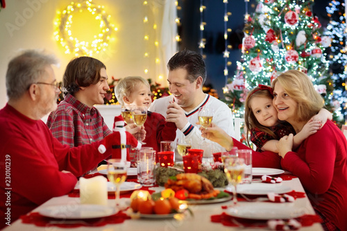 Family with kids having Christmas dinner at tree