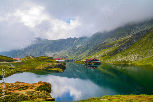 Glacial Balea lake near Transfagarasan road in the Carpathian Mountains, Romania, Eastern Europe. Wood cabin, chalet, hotel, cottage. Glacial, green grass, rocks, summer vacation, landscape.
