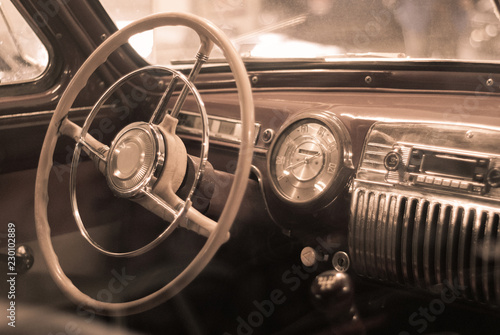 Blurred background - interior of a vintage car, styled as an old sepia photo with dust and scratches.. © Evgeny