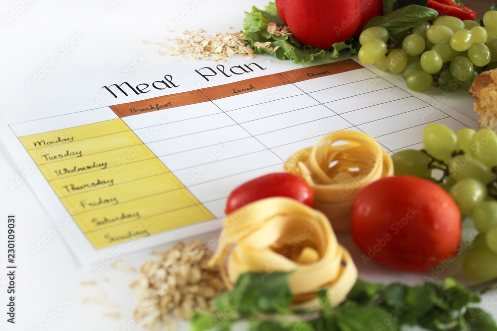 A meal plan for a week on a white table among products for cooking - pastas, basil, vegetables, cereals and spices. Concept healthy eating, dieting, slimming and weigh loss concept, top view, flat lay A meal plan for a week on a white table among products for cooking - pastas, basil, vegetables, cereals and spices. Concept healthy eating, dieting, slimming and weigh loss concept, top view, flat lay