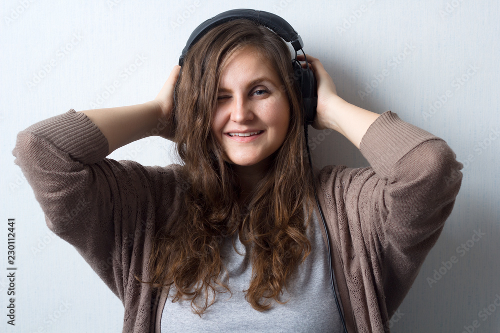 young beautiful caucasian woman with curly hair in sweater with headphones listen and enjoy favourite music , music lover, music fan lifestyle female portrait young beautiful caucasian woman with curly hair in sweater with headphones listen and enjoy favourite music , music lover, music fan lifestyle female portrait