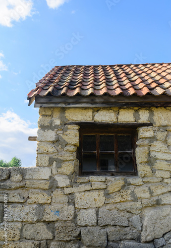 Window, stone wall and tile roof of an old building.