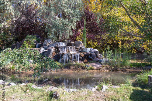 Waterfall in autumn surrounded by trees and with reflection in a pond in Mendoza Argentina
