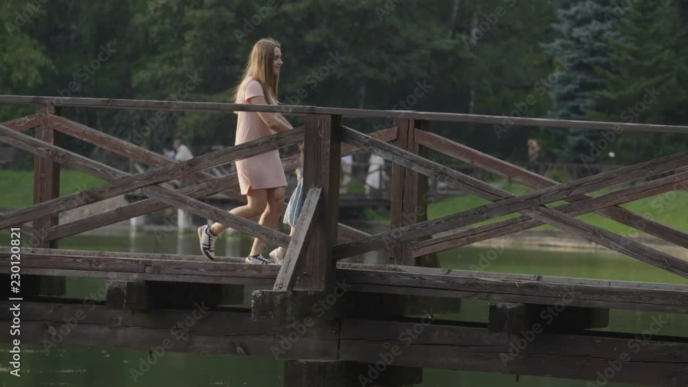 Baby with mom are running on a wooden bridge in the sunset light. Slow motion. Backlight sunset light. Happy family concept. Woman with long hair. Baby with mom are running on a wooden bridge in the sunset light. Slow motion. Backlight sunset light. Happy family concept. Woman with long hair.