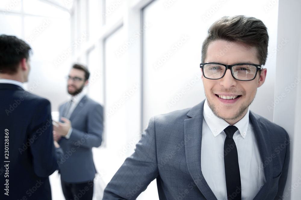 young businessman with glasses standing in the hallway office