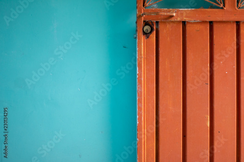 Orange steel door against blue wall detail © Monarca