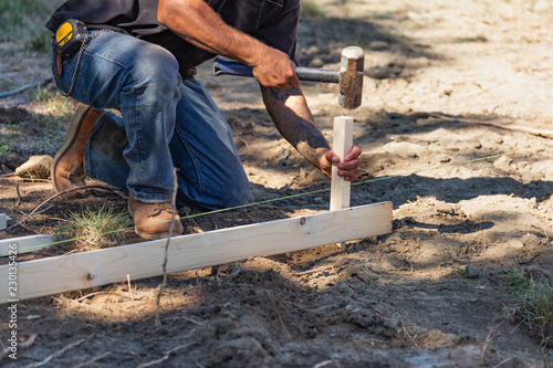 Fotografija Worker Installing Stakes and Lumber Guides At Construction Site