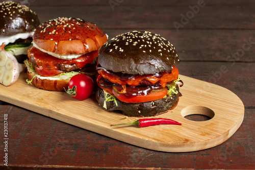 Four burgers on a light wooden board surface. Clouse-up.
