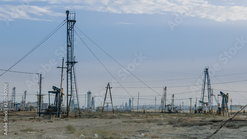 Desertous industrial landscape with oil pumps and rich modern city in background photo