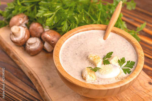 Tasty pureed mushroom soup in wooden bowl with ingredients