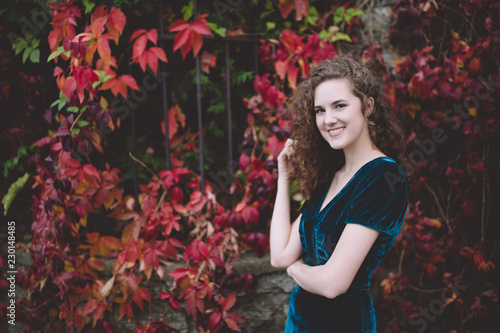 Beautiful curly hair girl in a dark blue velvet dress in an autumn park