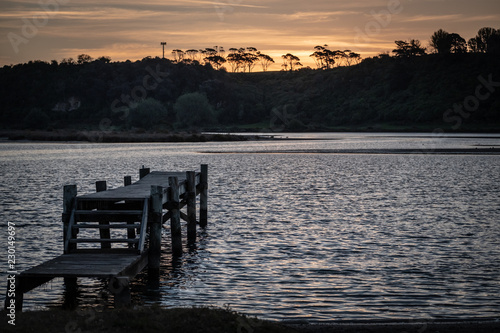 jetty at sunset with silhouette of trees in distance