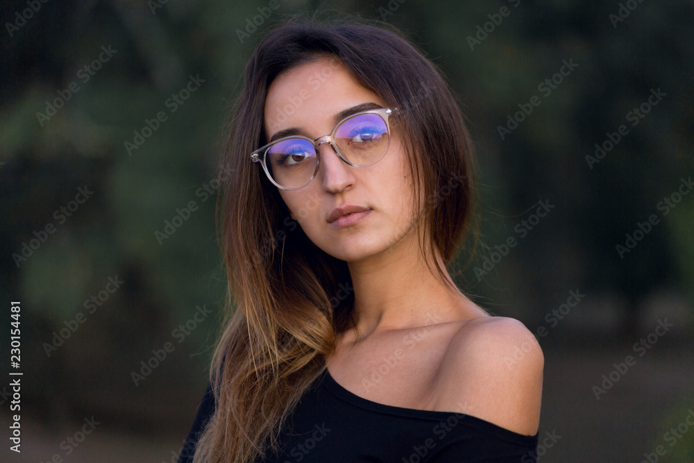 Beautiful portrait of a girl with glasses against the background of the forest, The concept of sexual teacher
