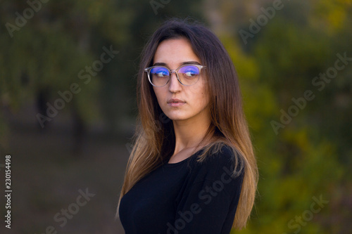 Beautiful portrait of a girl with glasses against the background of the forest, The concept of sexual teacher © Mountains Hunter