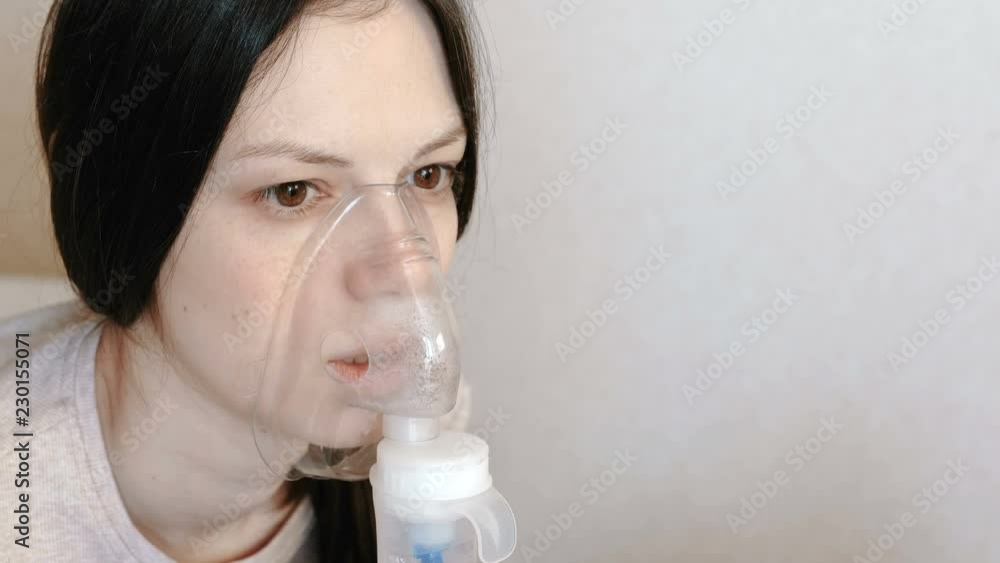 Use nebulizer and inhaler for the treatment. Closeup woman's face inhaling through inhaler mask. Front view. Use nebulizer and inhaler for the treatment. Closeup woman's face inhaling through inhaler mask. Front view.