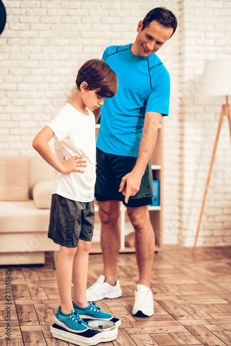 Boy in Sports Uniform Stand on Scales near Father