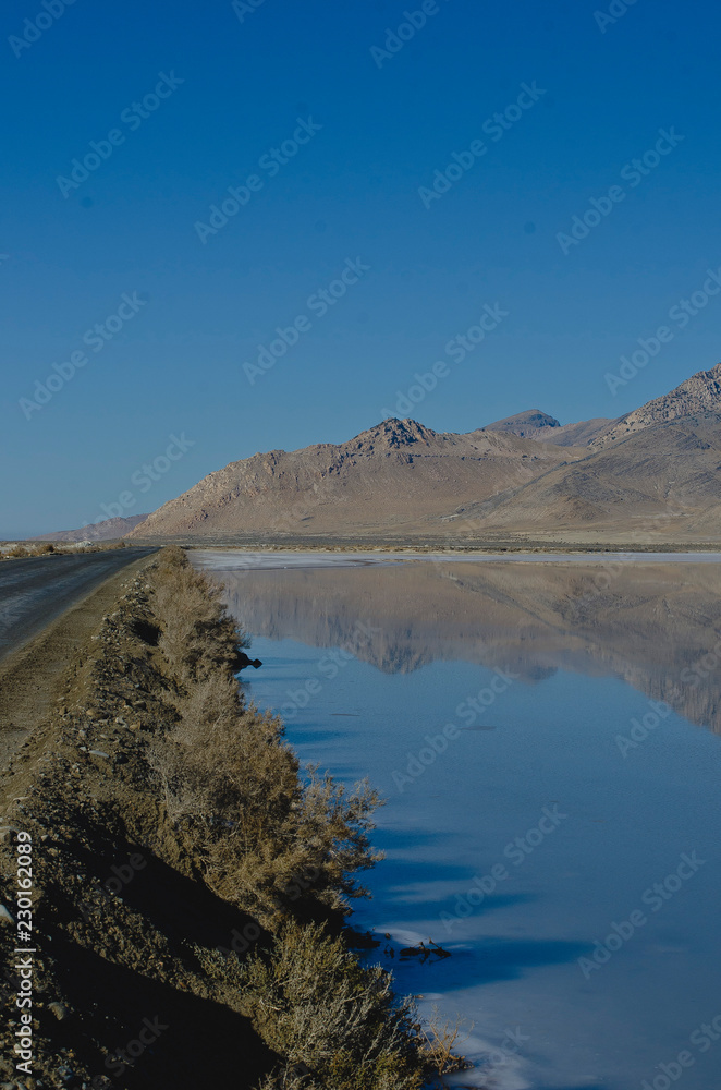 A long view of the raod running along the salt ponds  of the great salt lake in the morning light. 