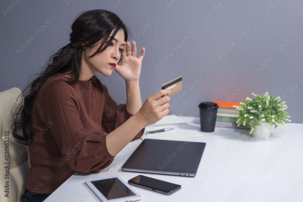 stressed woman holding credit card with laptop computer on table