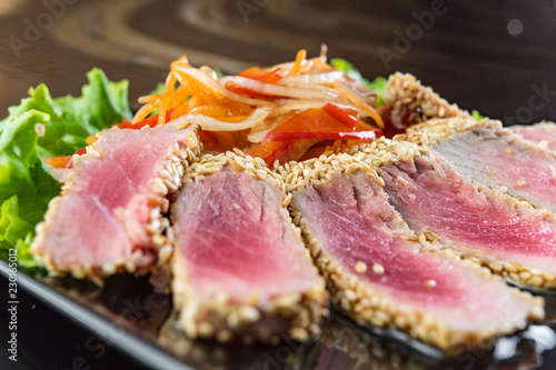 Close Up Still Life of Roasted Tuna Steaks Crusted with Herbs and Sesame Seeds on Dark Gray Surface