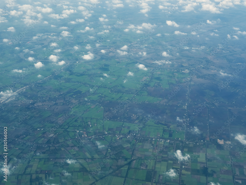 An aerial view of clouds and skies and fields from an airplane (flying over Southeast Asia - Thailand, Vietnam)