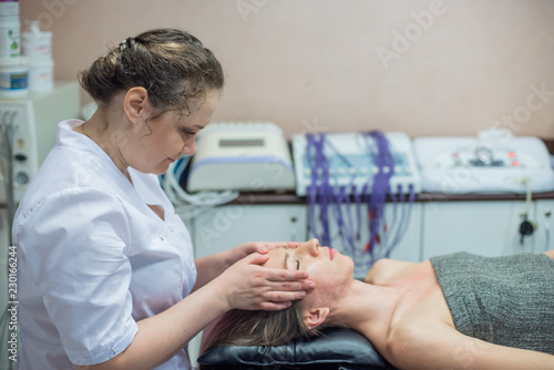Side view of the face of a young girl during a manual face massage at the spa. Anti-aging facial massage for a beautiful blonde woman. Masseuse doing shiatsu massage to woman