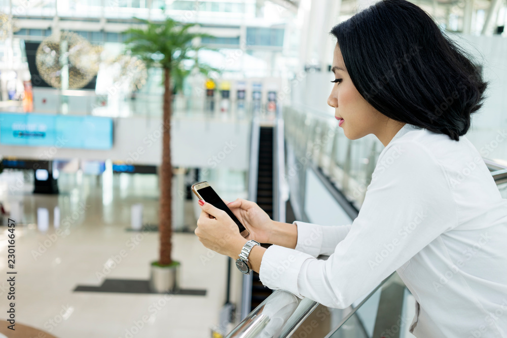 Beautiful woman using phone in airport terminal