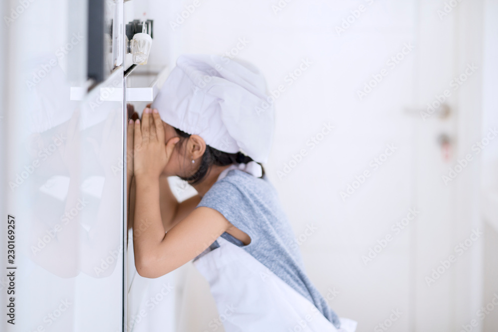 Little girl waiting for baking cookie in oven Little girl waiting for baking cookie in oven