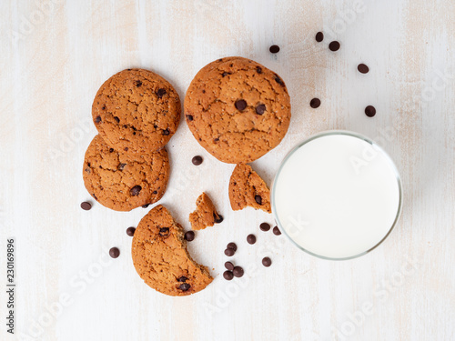 Oatmeal cookies with chocolate drops and milk in glass  healthy snack. Light background  white wooden table  top view