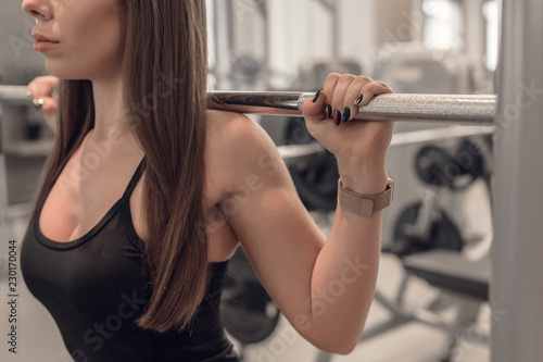 Closeup of athletic fit sportswoman doing exercise with barbell