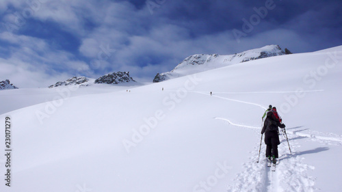 a group of backcountry skiers hike and climb to a remote moutain peak in Switzerland